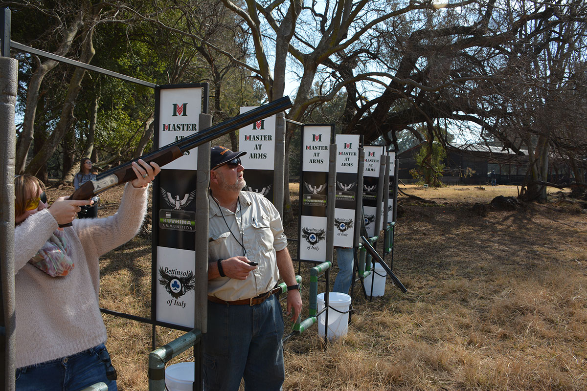 Shooter aiming at clay target with Range Officer coach